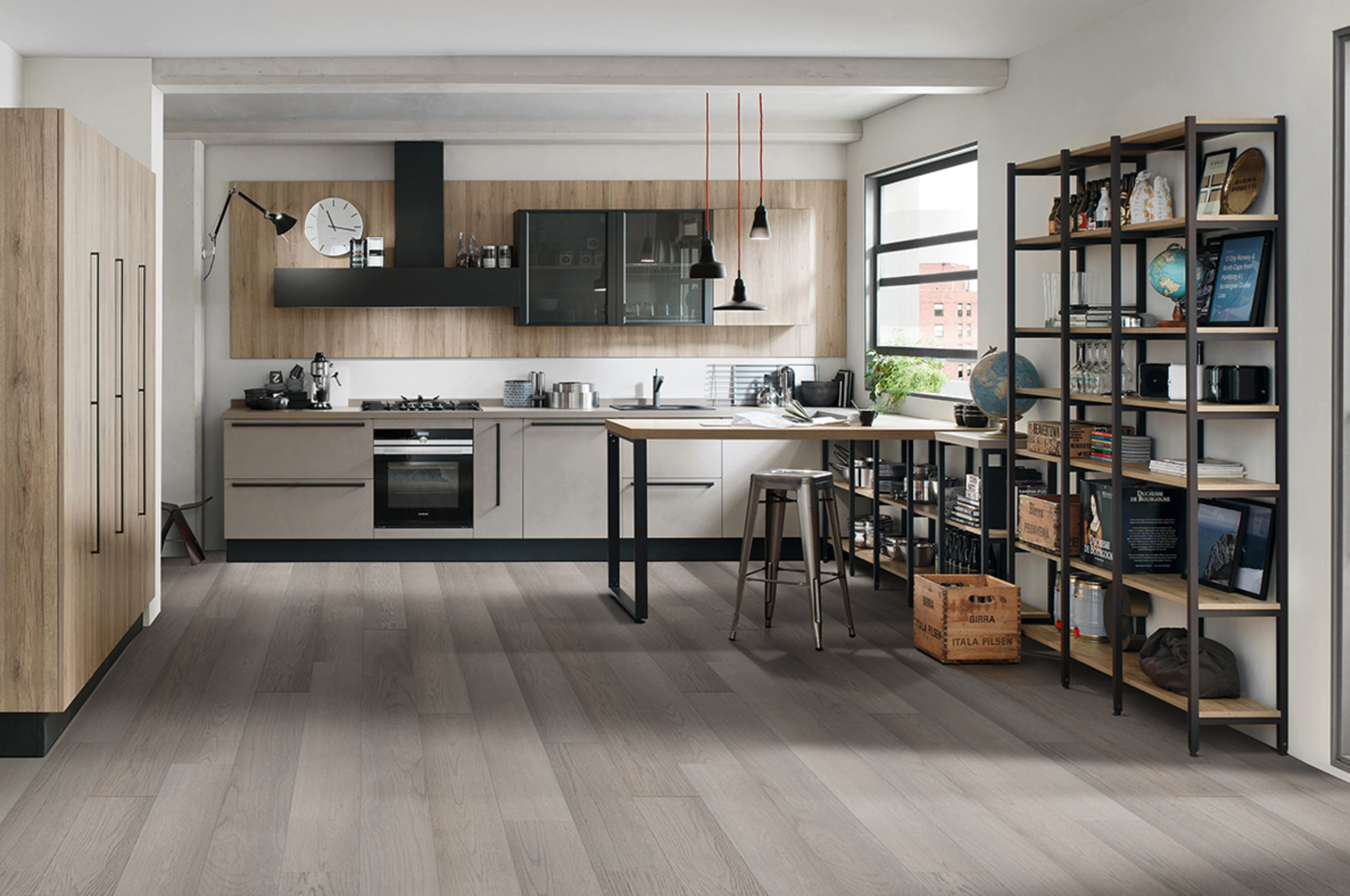 Modern kitchen with beige cabinets, red pendant lights, wooden island, black hood, oven, and bookshelf on wood floor.